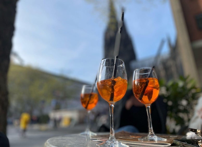 Three glasses of amber-colored drink with ice cubes on a table. 1
