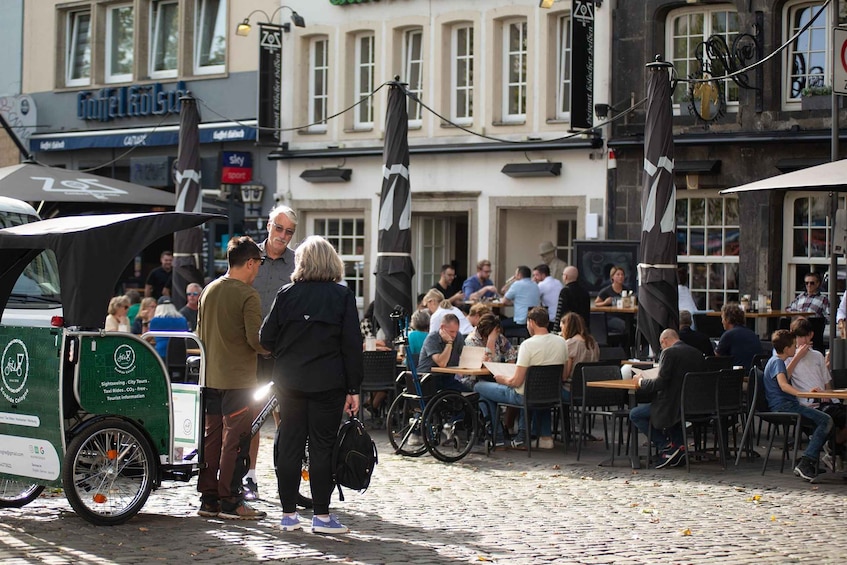 A busy outdoor café with people dining and a green taxi parked nearby. 4