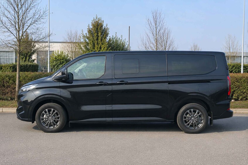 A black van parked on a road with trees and a building in the background. 5