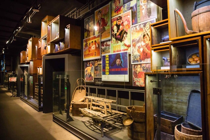 A museum exhibit with traditional wooden furniture and cultural artifacts, including posters and a display of a wooden bed frame. 5