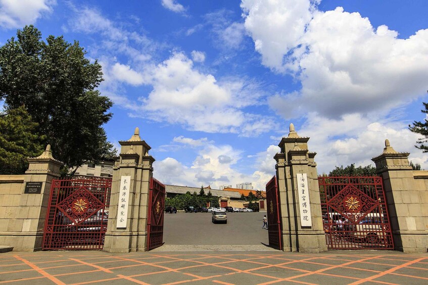 A gate with Chinese characters, a clear sky, and a parking lot. 1