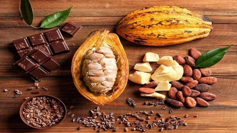 A cocoa pod, chocolate pieces, almonds, and cocoa beans on a wooden surface. 3