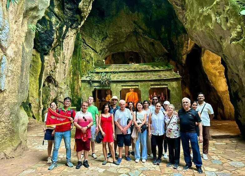A group of people standing in front of a cave with a Buddha statue inside. 2