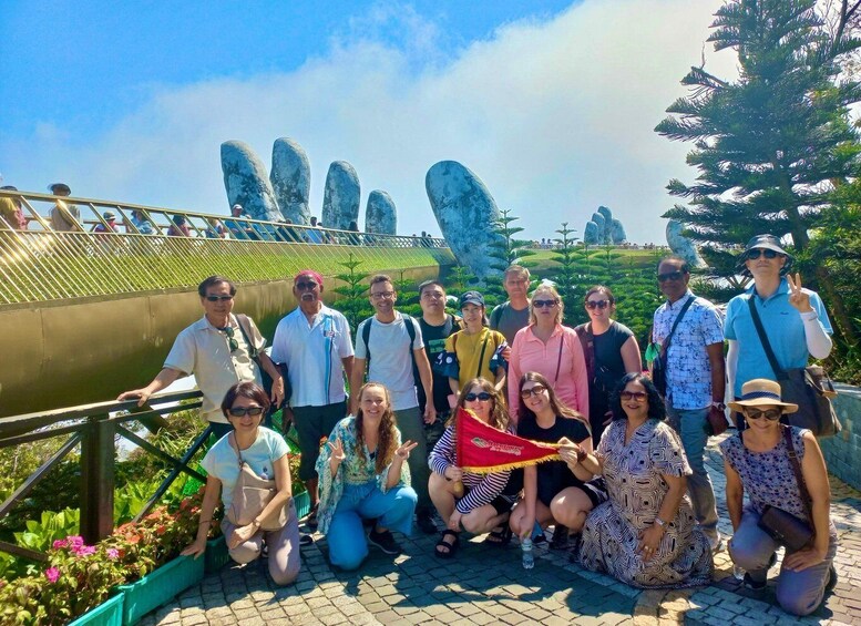 A group of people posing in front of a bridge with unique rock formations in the background. 1