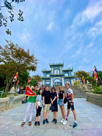 A group of people posing in front of a traditional gate with flags. 3