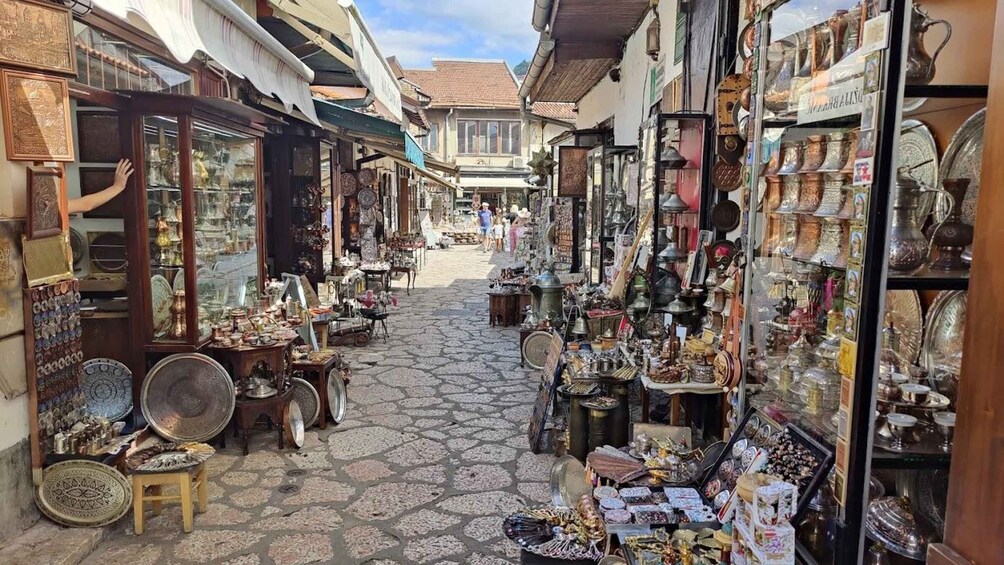 A narrow street with shops on both sides selling various items like pottery, jewelry, and textiles. 3