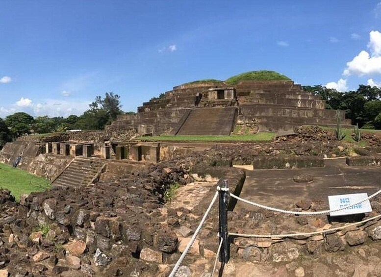 An ancient pyramid with a flat top, surrounded by ruins and a rope barrier. 2