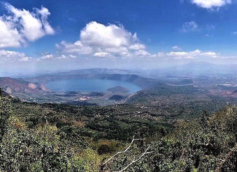 A volcanic crater surrounded by lush greenery and a clear blue sky. 4