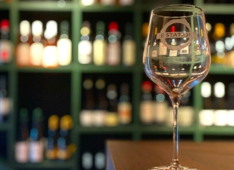 A glass with the word "STATION" on it, placed in front of a blurred background of bottles. 4