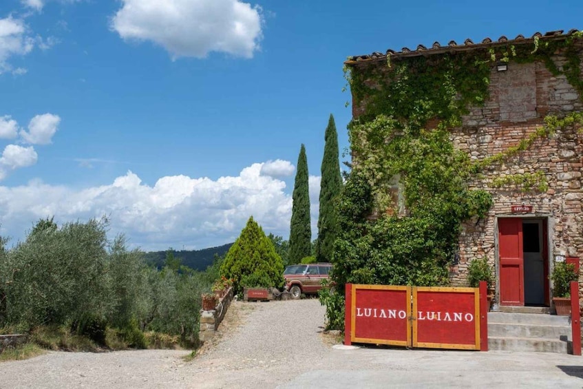 A rustic stone building with a red door, surrounded by greenery and a gravel path. 2
