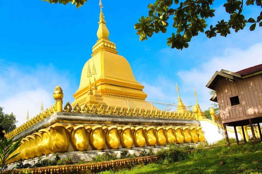 A golden stupa with a smaller spire, surrounded by a fence and a wooden structure. 2