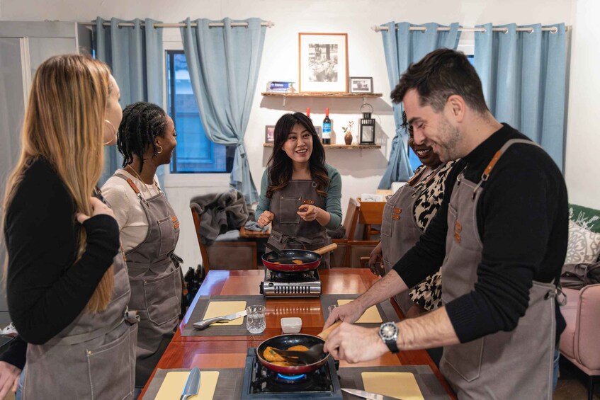 Four people cooking at a table with a portable stove. 1