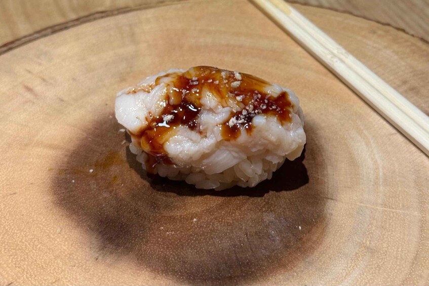 Sushi-rulla tumman kastikkeen kera tarjoiltuna puulautasella. 3