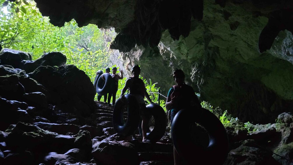 A group of people hiking through a rocky cave with sunlight filtering through. 4