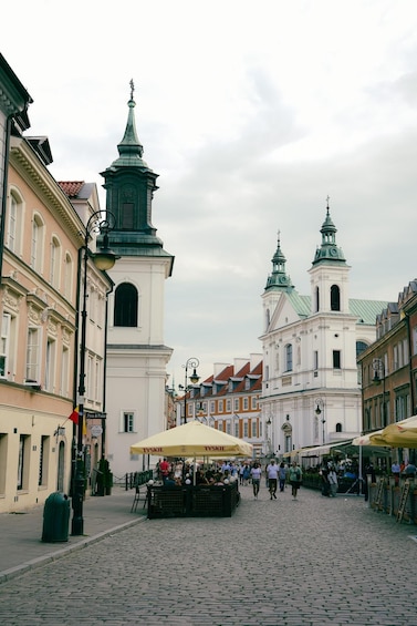 A cobblestone square with a market, historic buildings, and a church with two towers. 5
