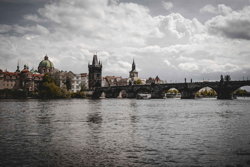 A river with a stone bridge, historic buildings, and a green-domed church. 1