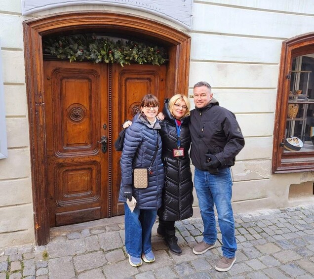 Three people standing in front of a wooden door with a wreath. 4