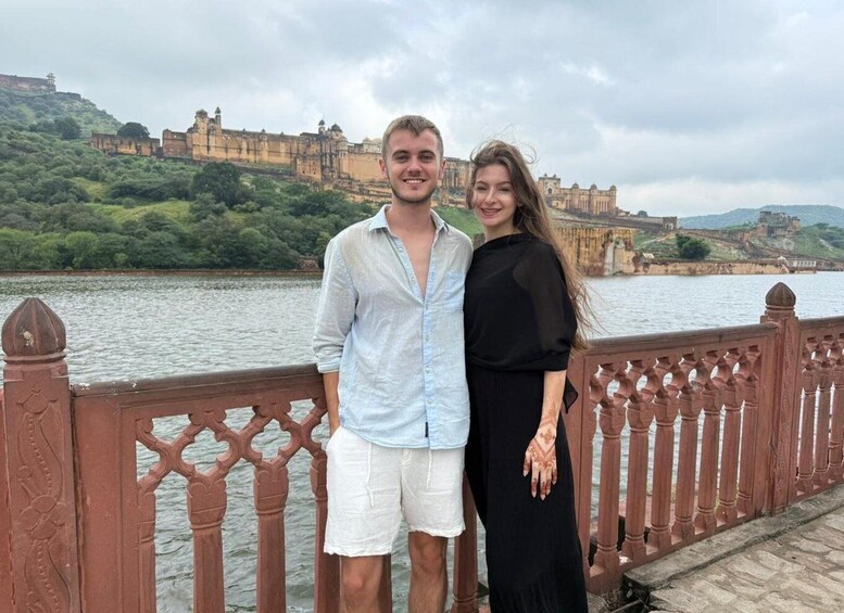 A couple standing on a bridge with a historic fort in the background. 5