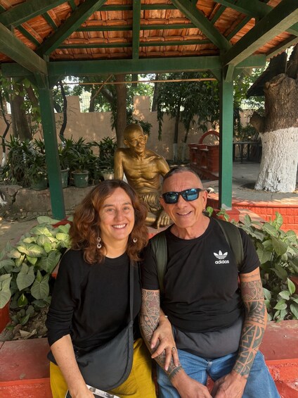 Two people sitting under a wooden pavilion with a golden statue in the background. 4