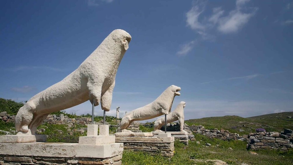 Two stone lion statues in a grassy area with a clear sky. 4