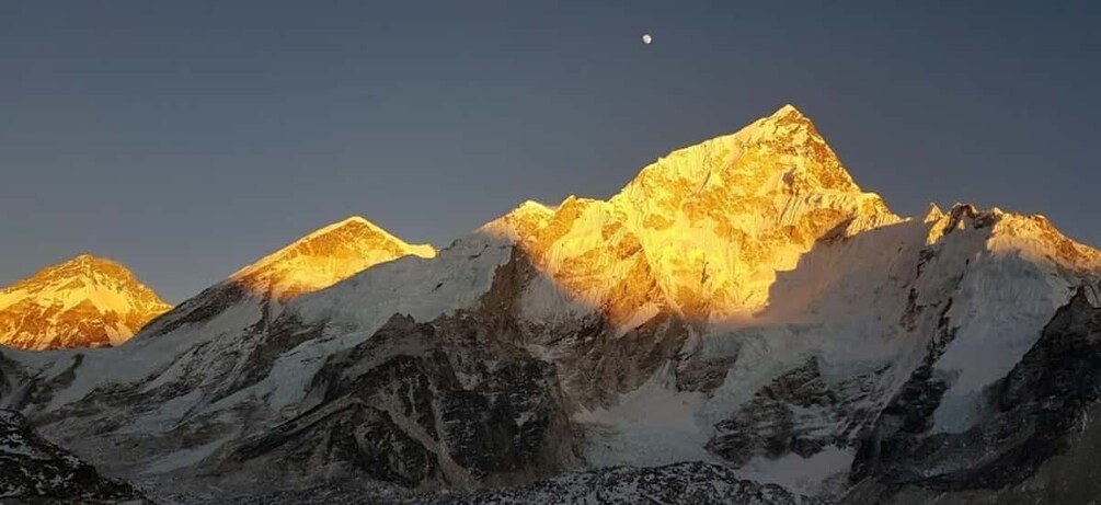 Una cadena montañosa con picos nevados y una luna creciente en el cielo. 1