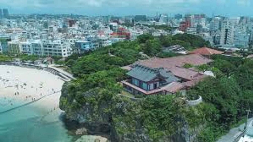 A coastal cityscape with a beach, dense greenery, and a mix of modern and traditional architecture. 2