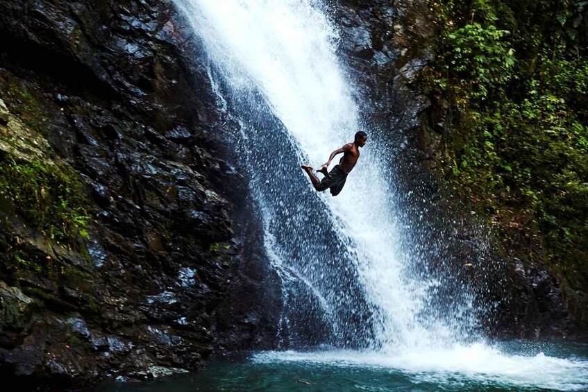 A person jumping off a cliff into a waterfall. 3