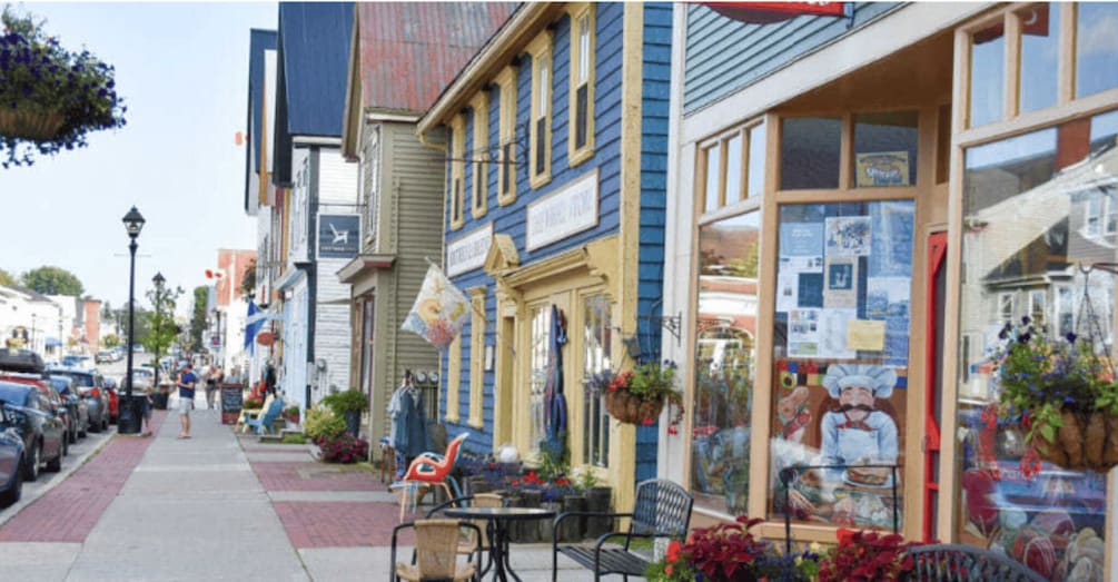 A street with parked cars, outdoor seating, and a variety of shops. 5