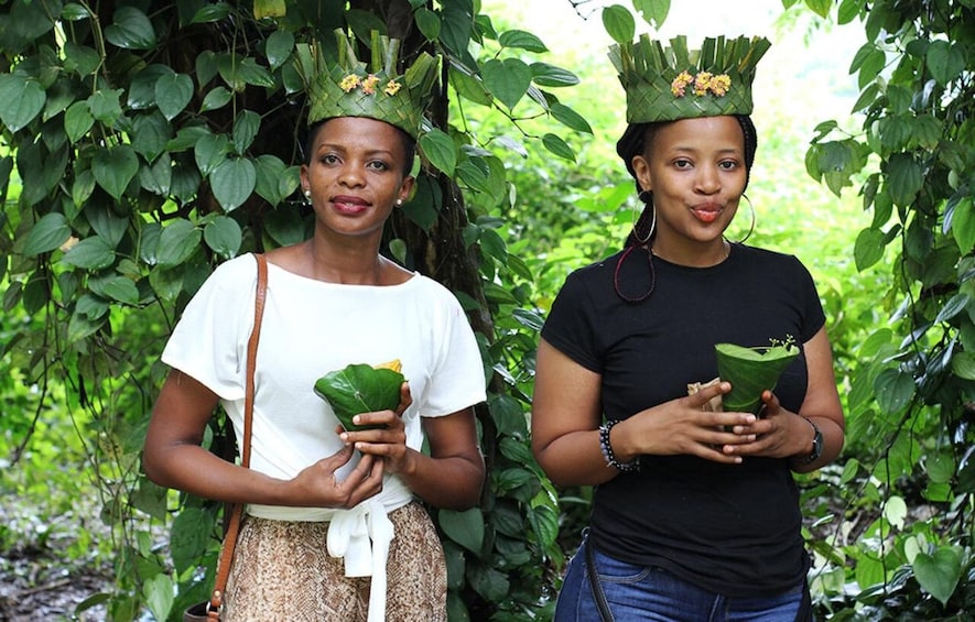 Two individuals holding green leaves, standing in a lush green environment. 2