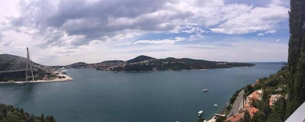 A coastal landscape with a cable-stayed bridge, a small island, and boats in the water. 5