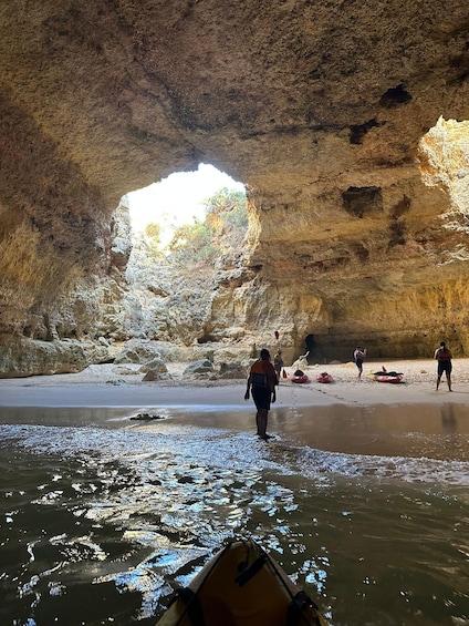 A cave entrance with a sandy beach and kayaks. 4