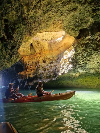 Two people kayaking in a cave with a large rock formation in the background. 2