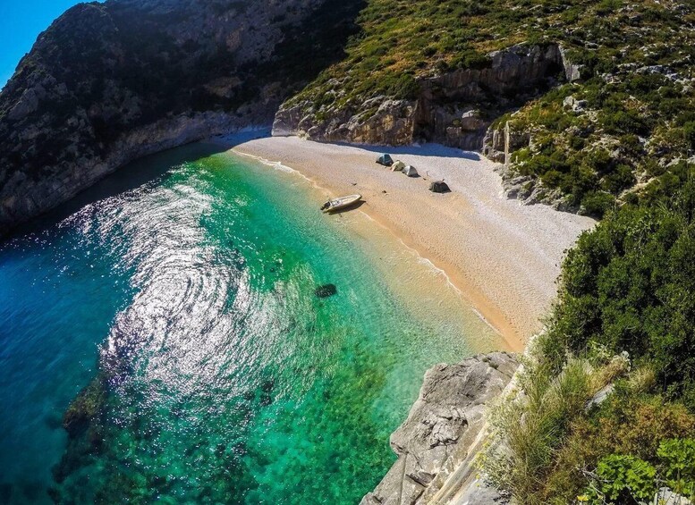 A coastal landscape with clear turquoise waters, a sandy beach, and rocky cliffs. 2