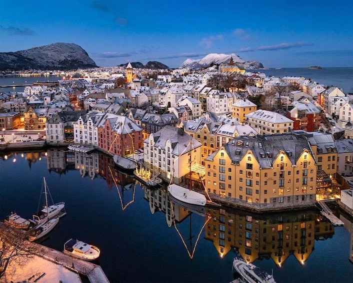 A snow-covered harbor town at dusk with illuminated buildings and boats. 1