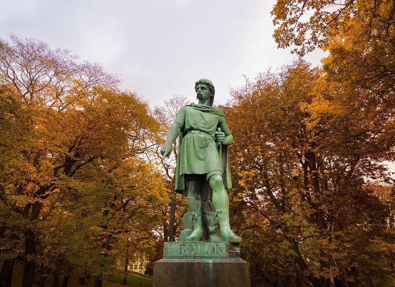 A statue of a historical figure named 'ROULON' in a park with autumn-colored trees. 4