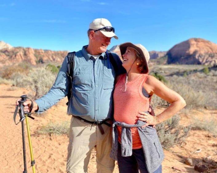 A couple hiking in a desert landscape with red rock formations in the background. 1