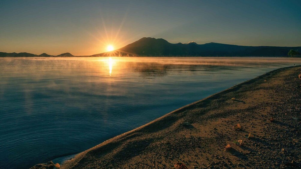 A calm lake at sunrise with mountains in the background. 4