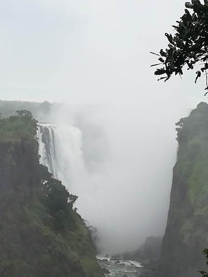 A waterfall cascading down a steep cliff surrounded by dense greenery. 4