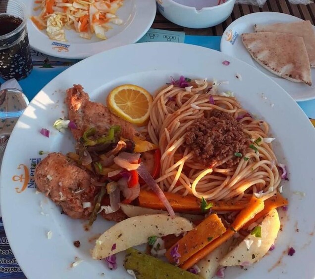 A plate of spaghetti with meatballs, vegetables, and lemon slices. 3