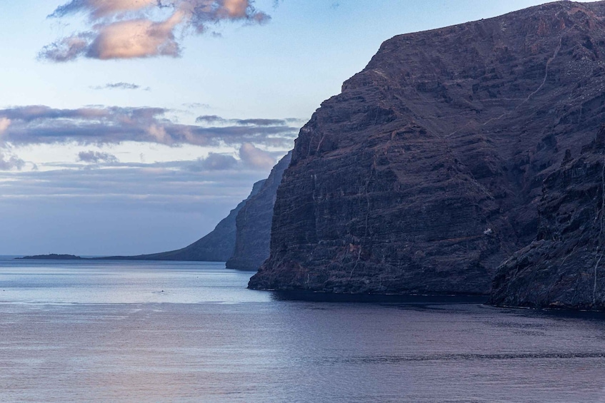 A coastal cliff with a calm sea and distant land. 1