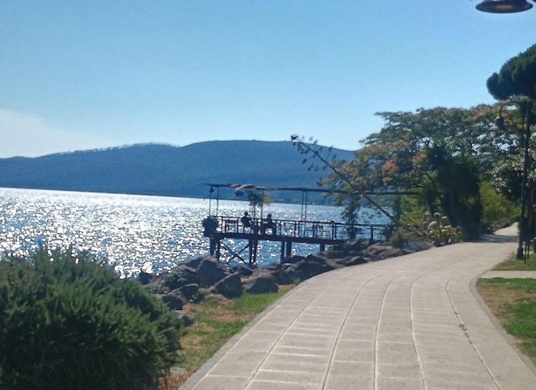 A paved walkway by a lake with a dock extending into the water. 4