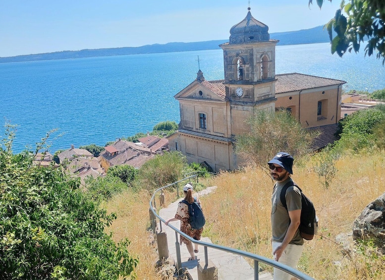 A coastal town with a bell tower, a clear blue sea, and a hilly landscape. 2