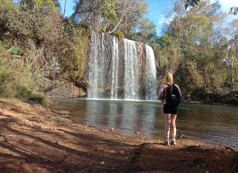 A waterfall in a forested area with a person standing by the water. 5
