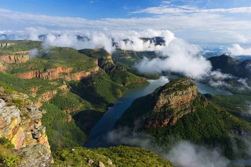 A mountainous landscape with a river, cliffs, and clouds. 4