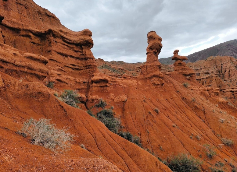 A red rock formation with unique shapes and sparse vegetation. 3