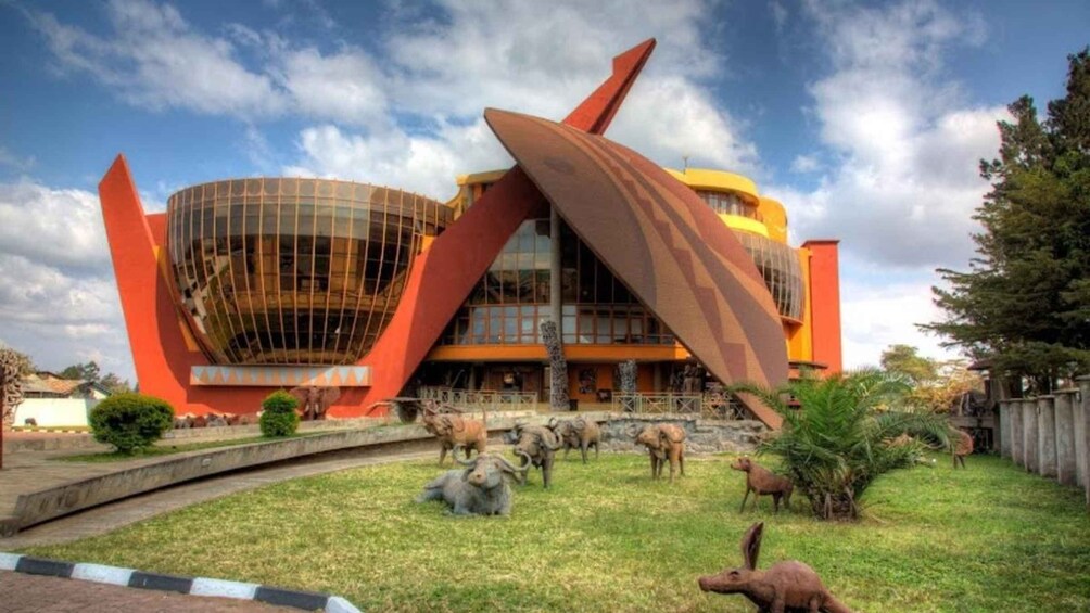 A modern building with a curved glass facade and angular red structures. 1