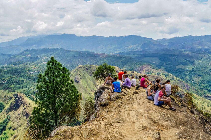 A group of people sitting on a rocky outcrop overlooking a mountainous landscape. 5