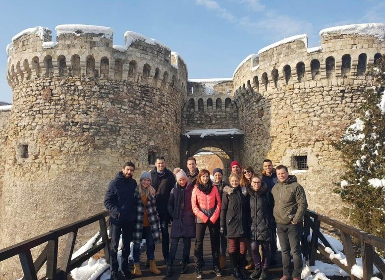 A group of people standing in front of a medieval castle with stone walls and arched windows. 4