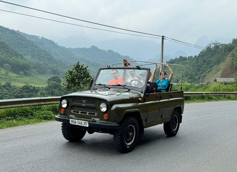 A green jeep with passengers on a road surrounded by lush greenery and hills. 4