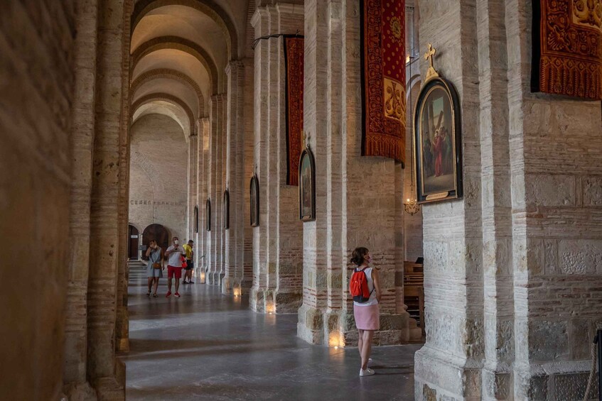 A cathedral interior with arched ceilings, stone columns, and religious paintings. 5